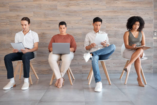 istock Interview, waiting room and people with technology ready for interviewing and we are hiring team. Laptop, tablet and reading of office employee group looking at digital information to prepare for job 1455317133