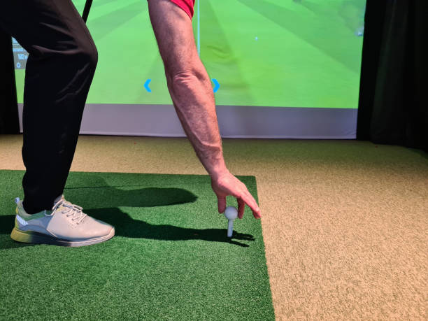 istock Golfer in studio put golf ball on tee to play on simulator 1455317547