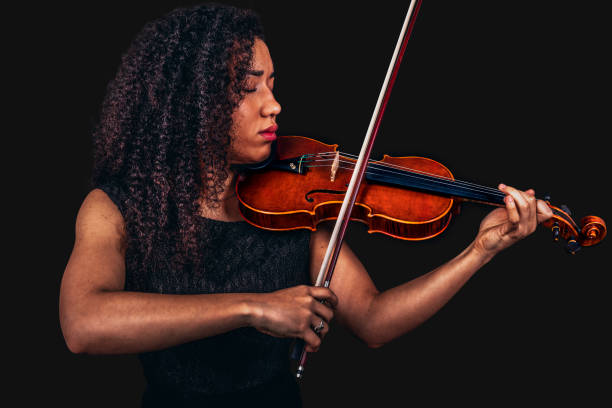 istock Beautiful young woman playing violin over black 1455321127
