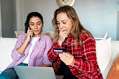 Stressed upset woman holding bank card and being surprised