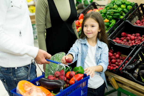 A young family with a daughter chooses vegetables in the supermarket.