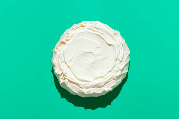 Pavlova cake in bright light, isolated on a green background Above view with a homemade pavlova cake, minimalist on a green table. Australian traditional dessert, crispy meringue crust filled with whipped cream pavlova stock pictures, royalty-free photos & images