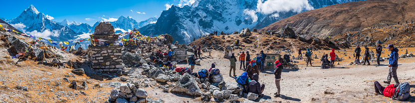 Crowds of hikers, mountaineers, Sherpa guides and porters at the memorial cairns at Chukpo Lari above Dugla on the Everest Base Camp Trail high in the Himalayan moutains of Nepal.