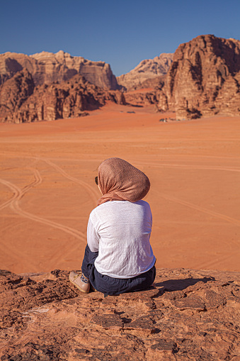 A vertical shot of a female sitting in Wadi Rum, Jordan