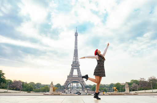 Beautiful young woman visiting paris and the eiffel tower. Parisian girl with red hat and fashionable clothes having fun in the city center and landmarks area