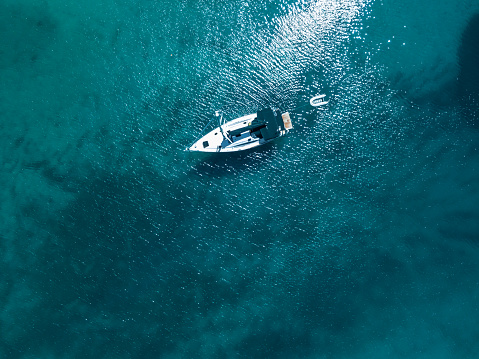 Anchored sailboat with rescue boat in shallow sea. High angle view photo from drone DJI Mavic Pro.