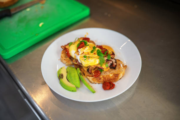 High Angle View of a Toast with Eggs Benedict and Avocado High angle view of delicious toast with eggs Benedict and avocado. Menu item from a food truck business, that includes bacon, eggs, rucola and tomatoes. Avocado Toast with Egg stock pictures, royalty-free photos & images