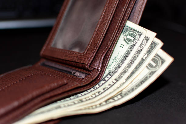istock A few dollars in a brown wallet on a black background 1455327128