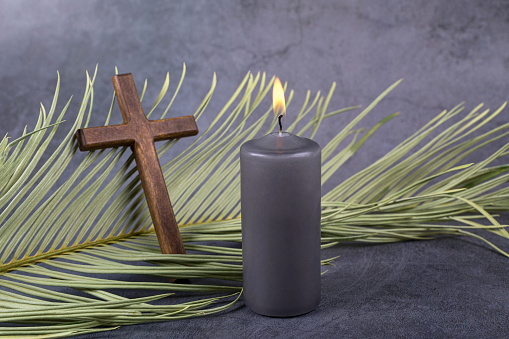 Catholic Cross with palm leaf and burning candle. Ash Wednesday, Lent season, Holy Week, Good Friday and Palm Sunday concept.