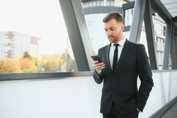 istock Confident young businessman using cell phone in the city. 1455329871