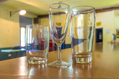 three empty glasses in different sizes and shapes on the counter of a venue with focus on the glasses