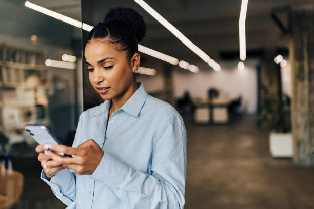 istock Successful African businesswoman using a phone while standing at the office. 1455331597