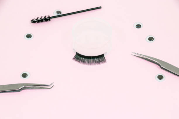 istock Eyelash extension. Black eyelash extensions, tweezers and an eyelash brush on a pink background. 1455336027