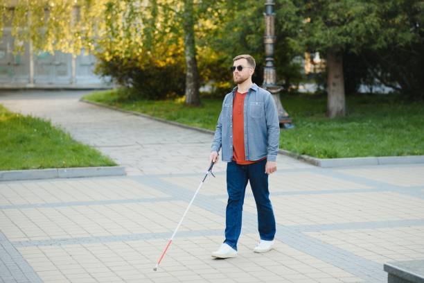 young blind man with white cane walking across the street in city young blind man with white cane walking across the street in city. blind persons cane stock pictures, royalty-free photos & images