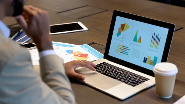 Close up of Businessman working on a laptop with financial charts and graphs