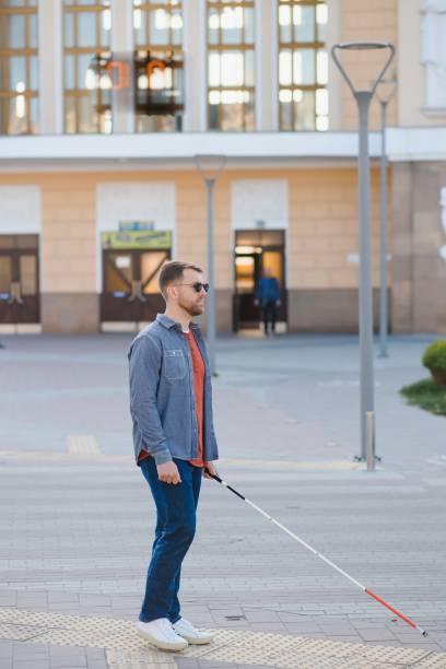 istock Young handsome blinded man walking with stick in town 1455339207