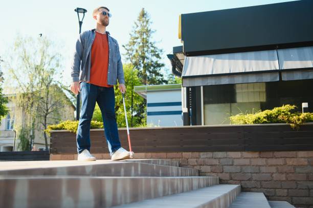 istock Young handsome blinded man walking with stick in town 1455340241