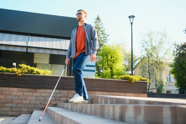 istock Young handsome blinded man walking with stick in town 1455340243