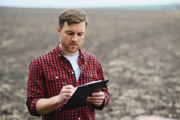 istock farmer standing in a plowed field. Agriculture, crop concept. 1455341079