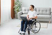 Man in wheelchair working on laptop in living room