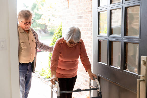 Caring spouse guides his wife through the front door