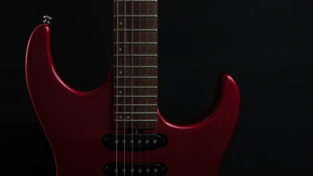 istock A vintage electric guitar standing upright with textured noir concept as black silver wallpaper. Music concept 1455343165