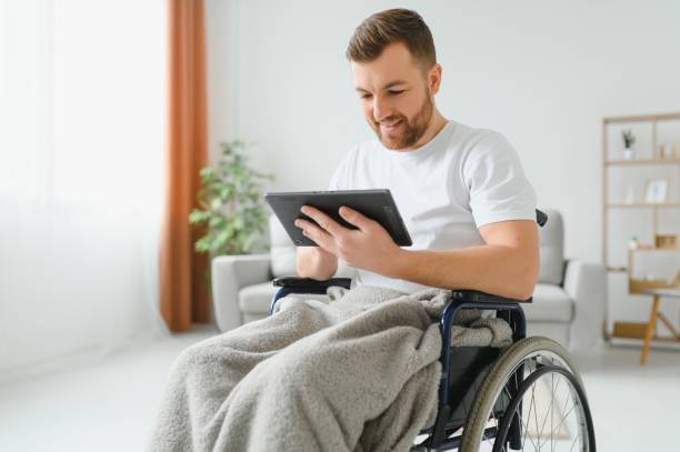 istock Modern young disabled man in wheelchair having video call 1455343260