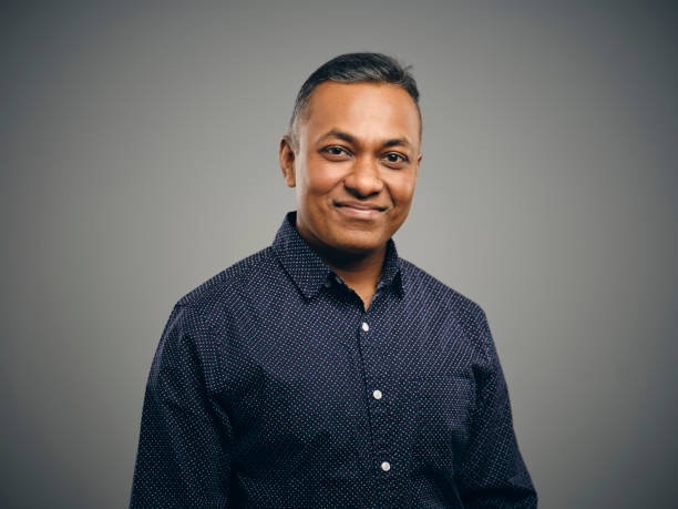 Portrait of an Indian Man A studio portrait of an Indian man against a brown background. headshot stock pictures, royalty-free photos & images