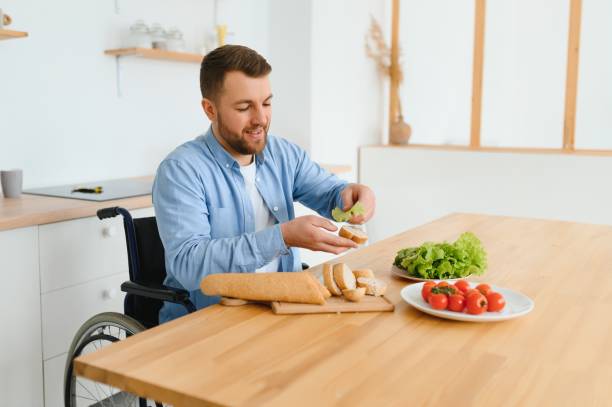 istock man in a wheelchair cuts vegetables in the kitchen. 1455344397