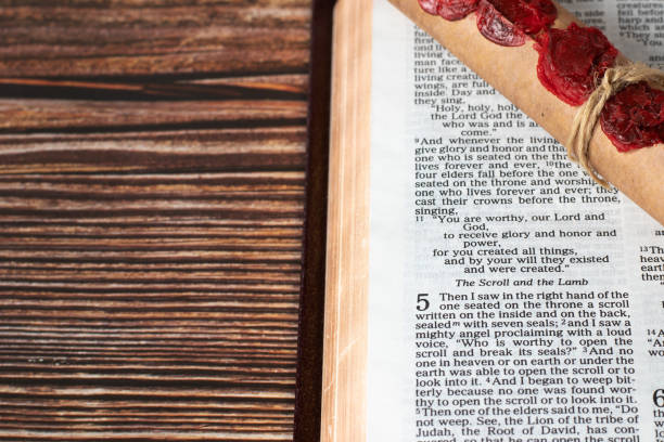 istock Ancient scroll with seven seals and open holy bible revelation book on wooden table with copy space, top view 1455346803