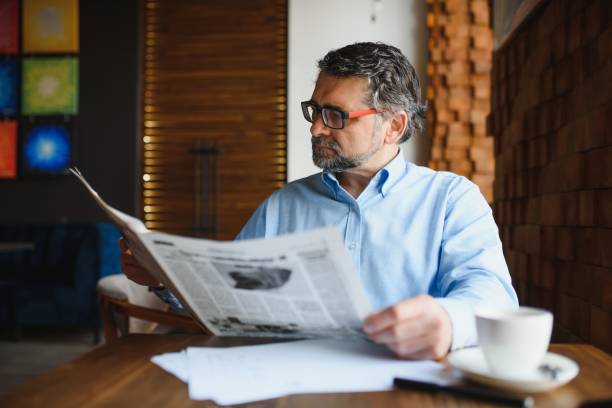 istock coffee break. man drinking coffee and reading newspaper in cafe bar 1455347039