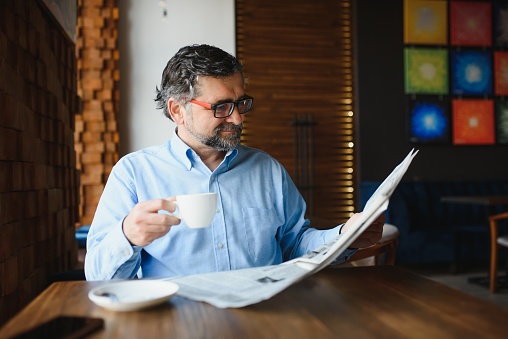 Business man reading a newspaper, cafe backgrounds.