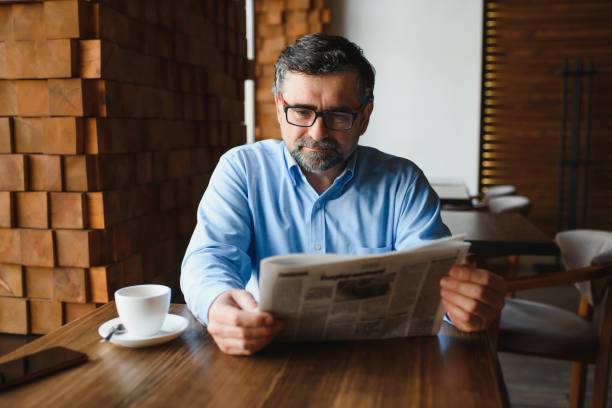 istock active senior man reading newspaper and drinking coffee in restaurant 1455347058