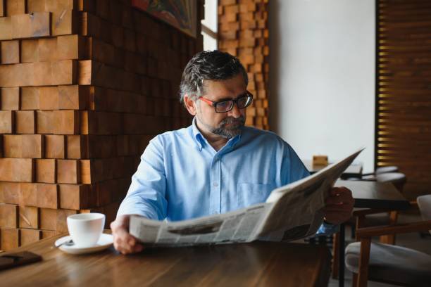 istock coffee break. man drinking coffee and reading newspaper in cafe bar 1455347061