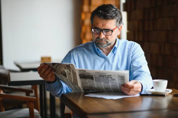 istock active senior man reading newspaper and drinking coffee in restaurant 1455347978