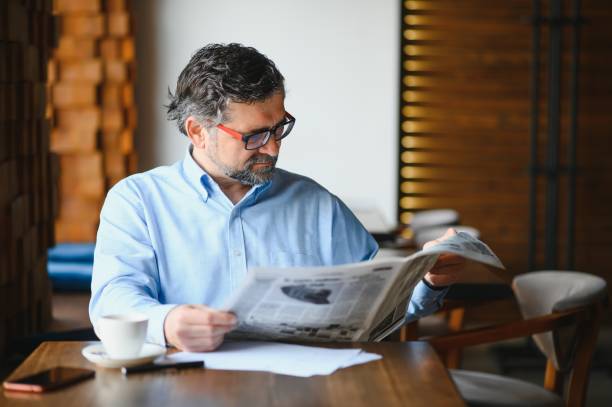istock active senior man reading newspaper and drinking coffee in restaurant 1455348606