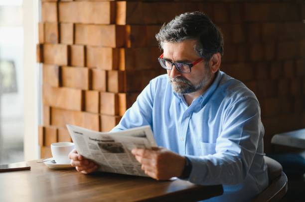 istock coffee break. man drinking coffee and reading newspaper in cafe bar 1455348609