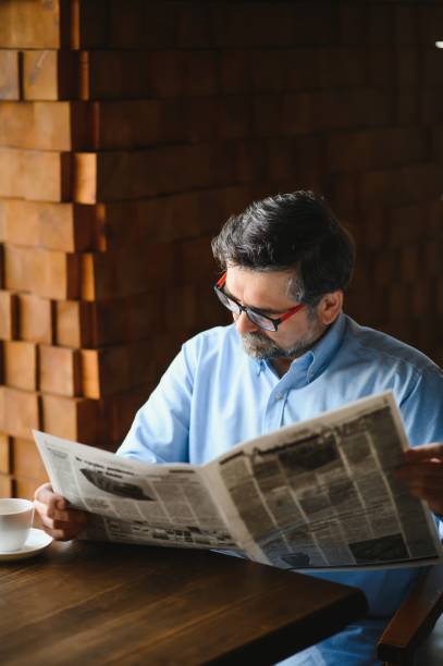 istock active senior man reading newspaper and drinking coffee in restaurant 1455348710