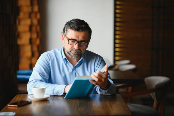 istock Mature handsome man reading a book in a cafe 1455348837