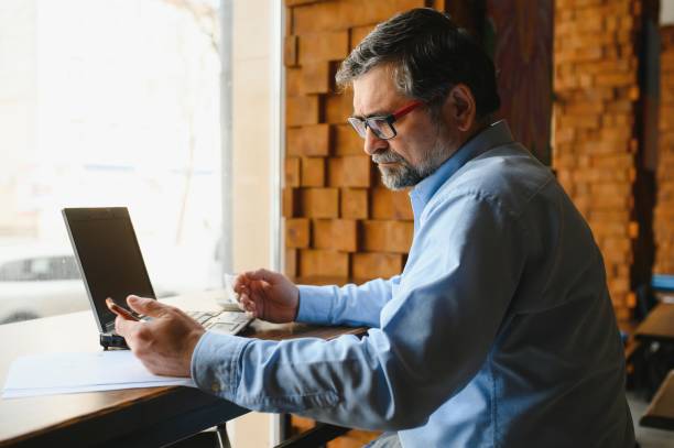 istock Senior male freelancer working on laptop in cafe. remote work concept. 1455349384