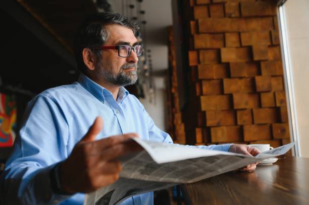 istock coffee break. man drinking coffee and reading newspaper in cafe bar 1455349589