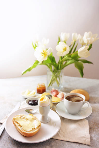 istock Breakfast table with flowers, bun, cooked egg, coffee and more, served with love at Sunday, birthday, valentines ore mothers day, light background, copy space, selected focus 1455353023