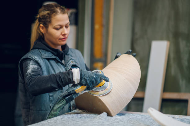 istock Woman carpenter using an electric sander in a workshop or factory 1455359698