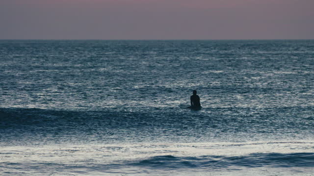 Surfer Waiting for a Wave at Sunset