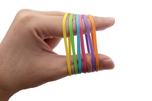 Close up of person hand pulling colorful multi color rubber bands around his fingers, isolated on white background