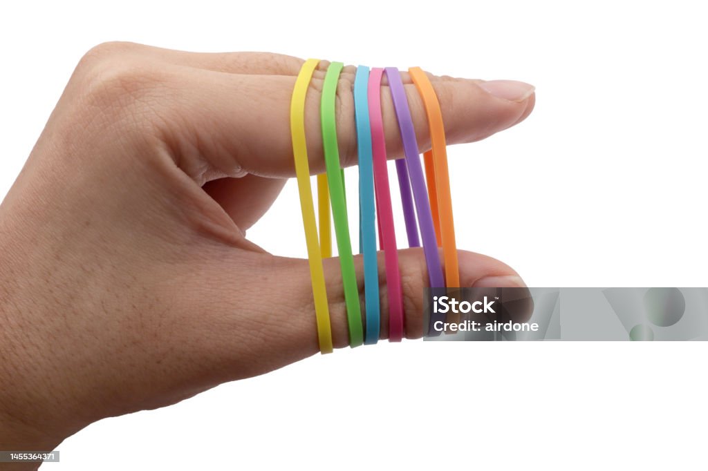 Close up of person hand pulling colorful multi color rubber bands around his fingers, isolated on white Close up of person hand pulling colorful multi color rubber bands around his fingers, isolated on white background Aiming Stock Photo