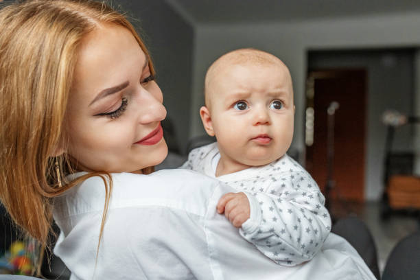 la mère s’occupe du nouveau-né à la maison. une mère souriante tient dans ses bras sa fille de deux mois - patient male nurse nurse hospital photos et images de collection