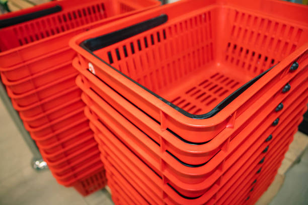 Stack of empty, plastic, red shopping baskets in a supermarket, closeup