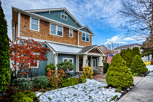 Photo of a modern American two-story suburban home on a snowy winter day with blue sky