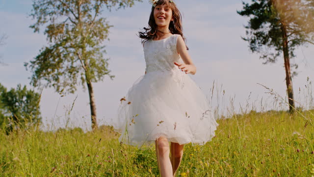 TIME WARP Little girl in a white dress runs in high grass